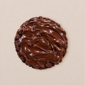 A single chocolate cookie topped with thick, glossy chocolate frosting, photographed from directly above on a plain beige background.